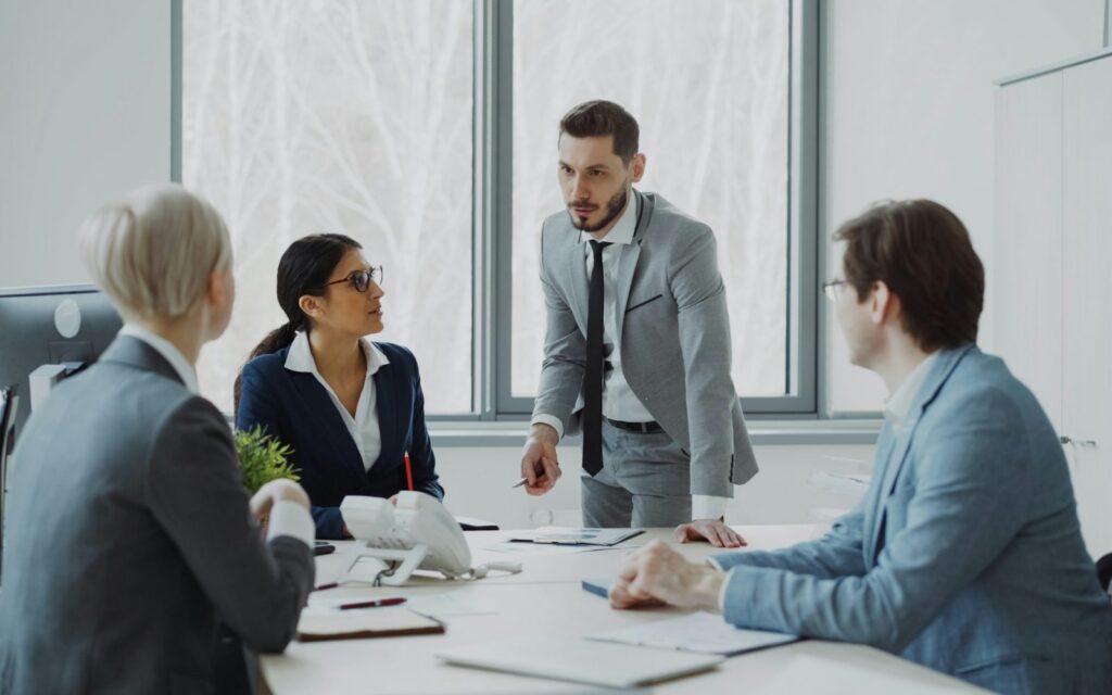 Fractional COO leading a team meeting Operations leader running a leadership team meeting around an office table
