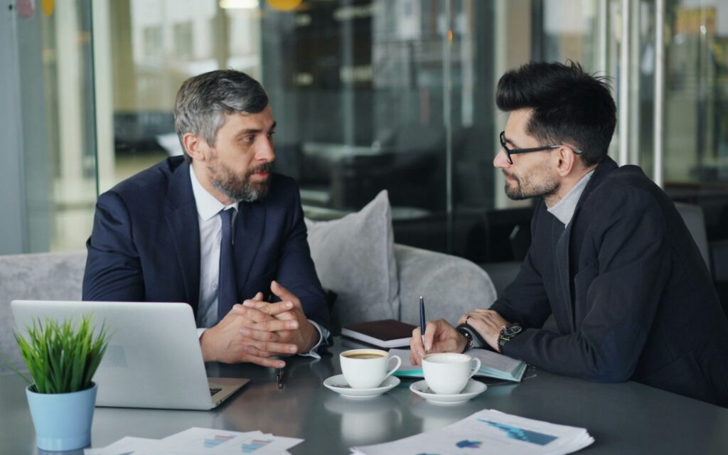Fractional executive advising a business owner Senior executive advising a business owner across a meeting table