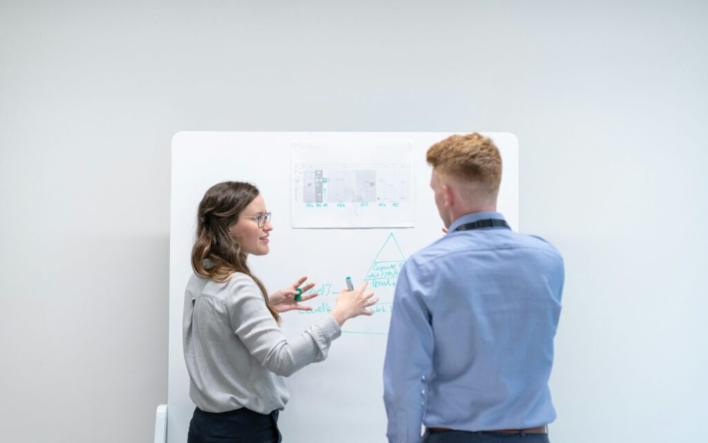 Fractional integrator planning at a whiteboard Two business partners turning ideas into a plan at a whiteboard